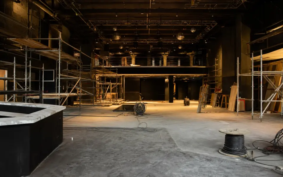 Illustration: the empty interior of a nightclub being rebuilt, scaffolding on a bare floor