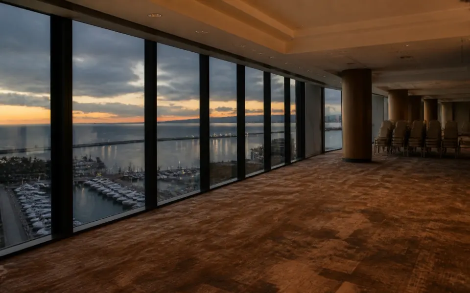 Illustration: an empty top-floor event space with stacked banquet chairs and a wall of windows